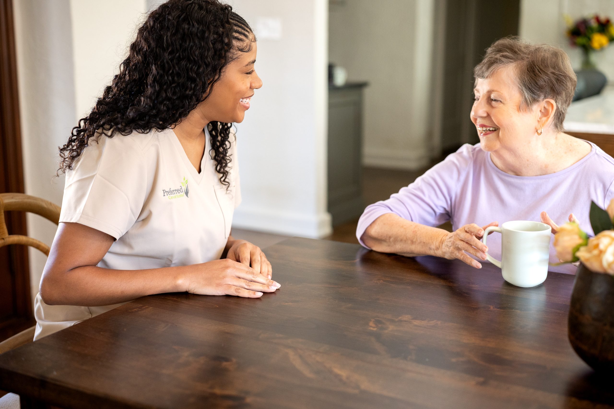 A Preferred Care at Home caregiver talking with an older woman at her dining table in San Antonio
