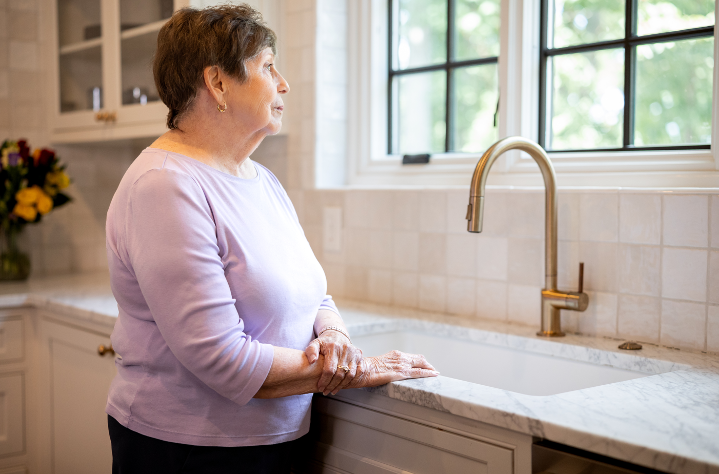 An older woman stands by a sink, representing specialized dementia in-home care for Boca Raton families.