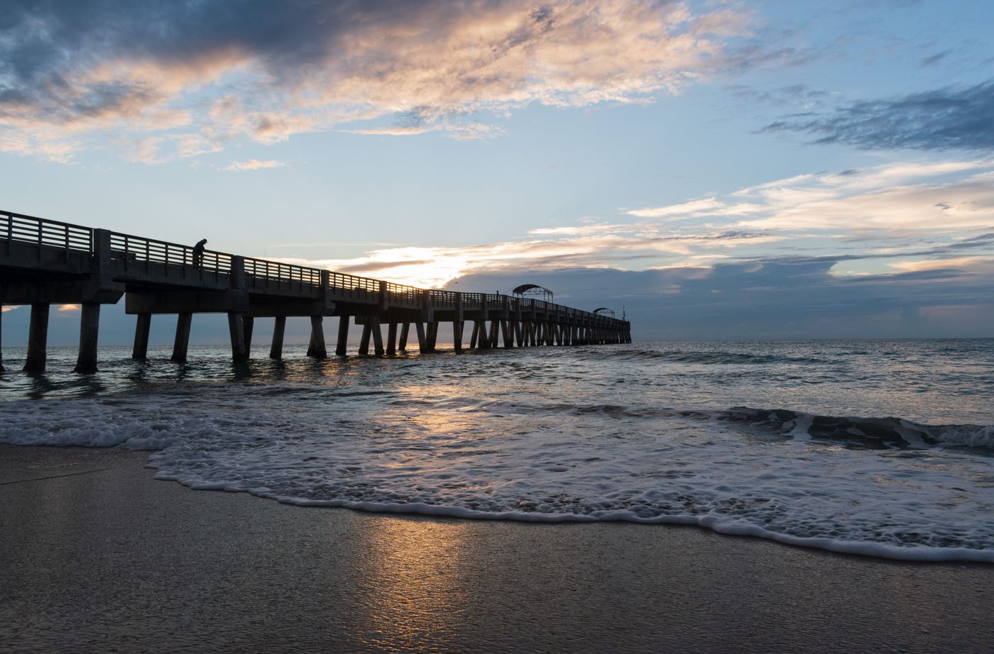 Sunset over the pier in Fort Myers, Florida, with vibrant colors reflecting on Lake Worth's calm waters.