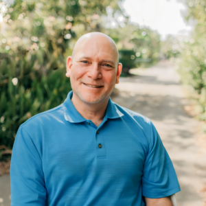 A smiling bald man in a blue shirt, identified as Len Weiss.