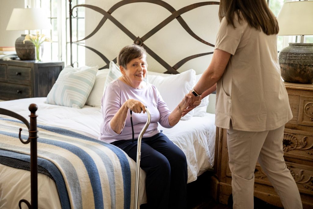 Older woman with caregiver providing supportive bedside care in a calm home environment