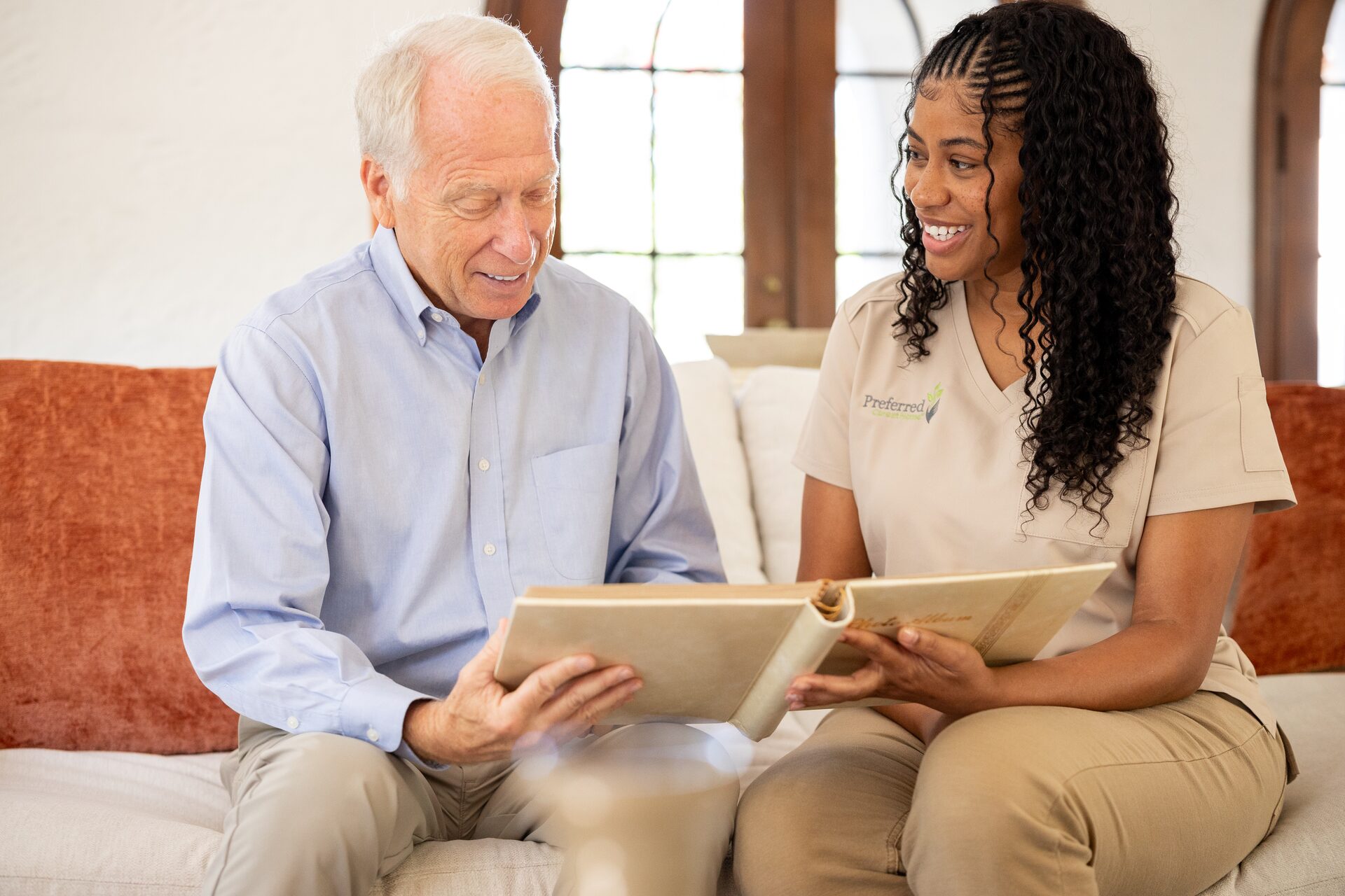A caregiver and senior man look through a photo album together — gentle companionship that supports emotional recovery when words are hard to find.