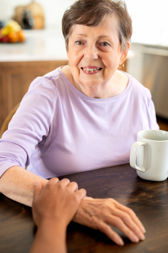 A woman enjoys a cup of coffee at a table, symbolizing the importance of coordinated home care with healthcare professionals.