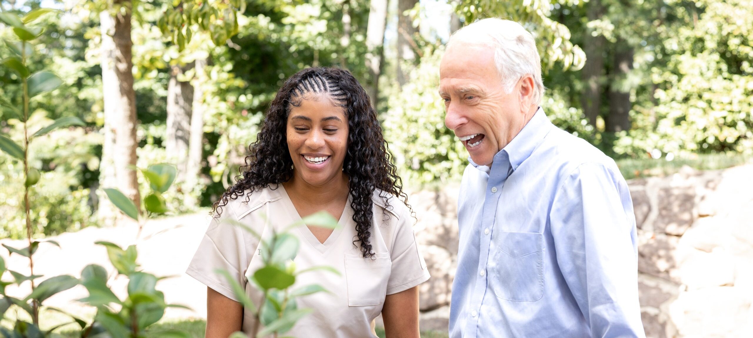 A Preferred Care at Home caregiver walking with a smiling senior in a sunny garden