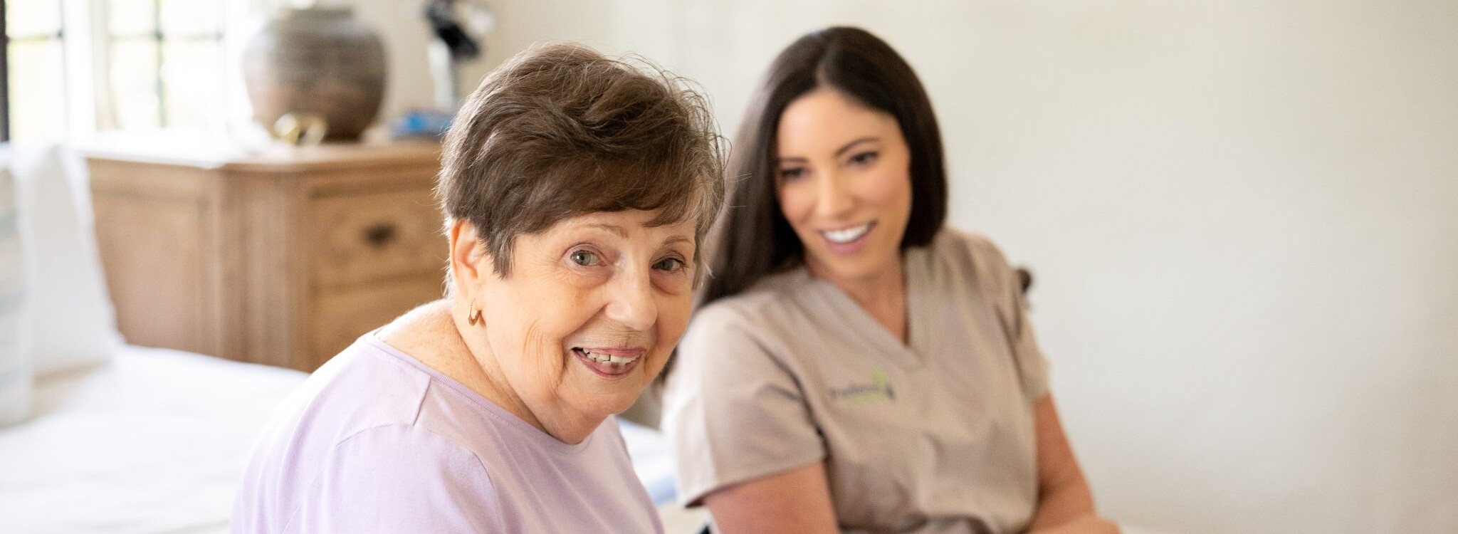 Senior woman with caregiver smiling at home — building a routine after a stroke
