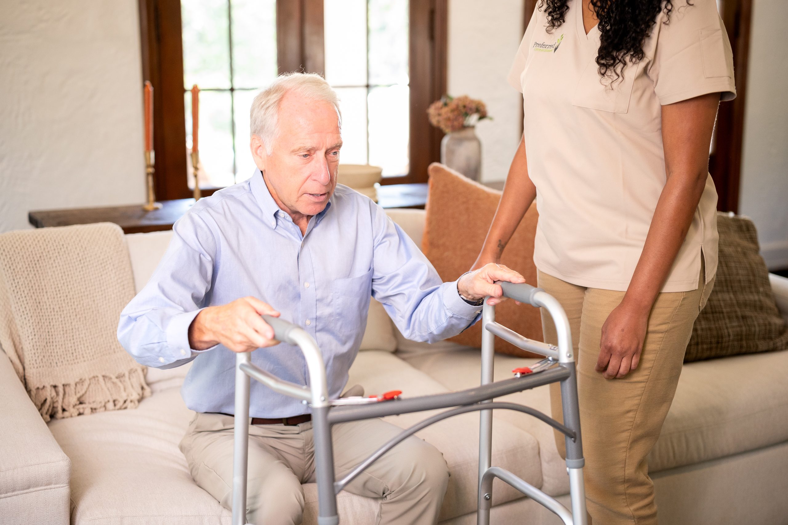 A woman is helping an elderly man with a walker, demonstrating care and assistance in their interaction.