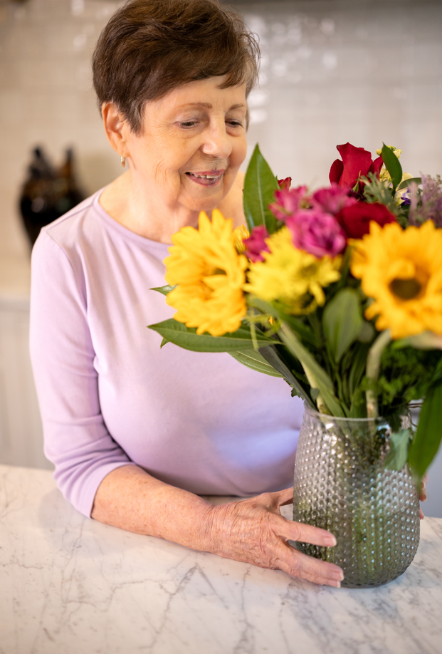 A woman holding a vase of flowers, symbolizing care and support in a specialized dementia and Alzheimer's respite setting.