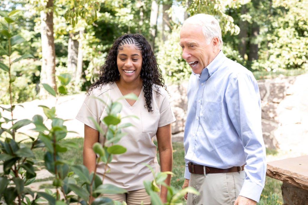 A man and woman enjoying time together in a lush garden surrounded by blooming flowers.