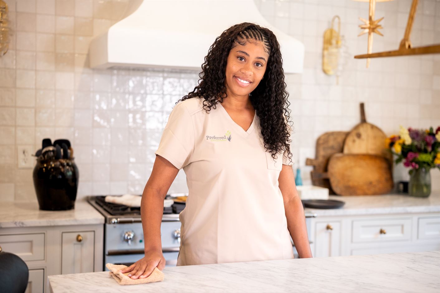 A woman presents a tray of cookies to an older woman, both smiling in a cozy, inviting environment.