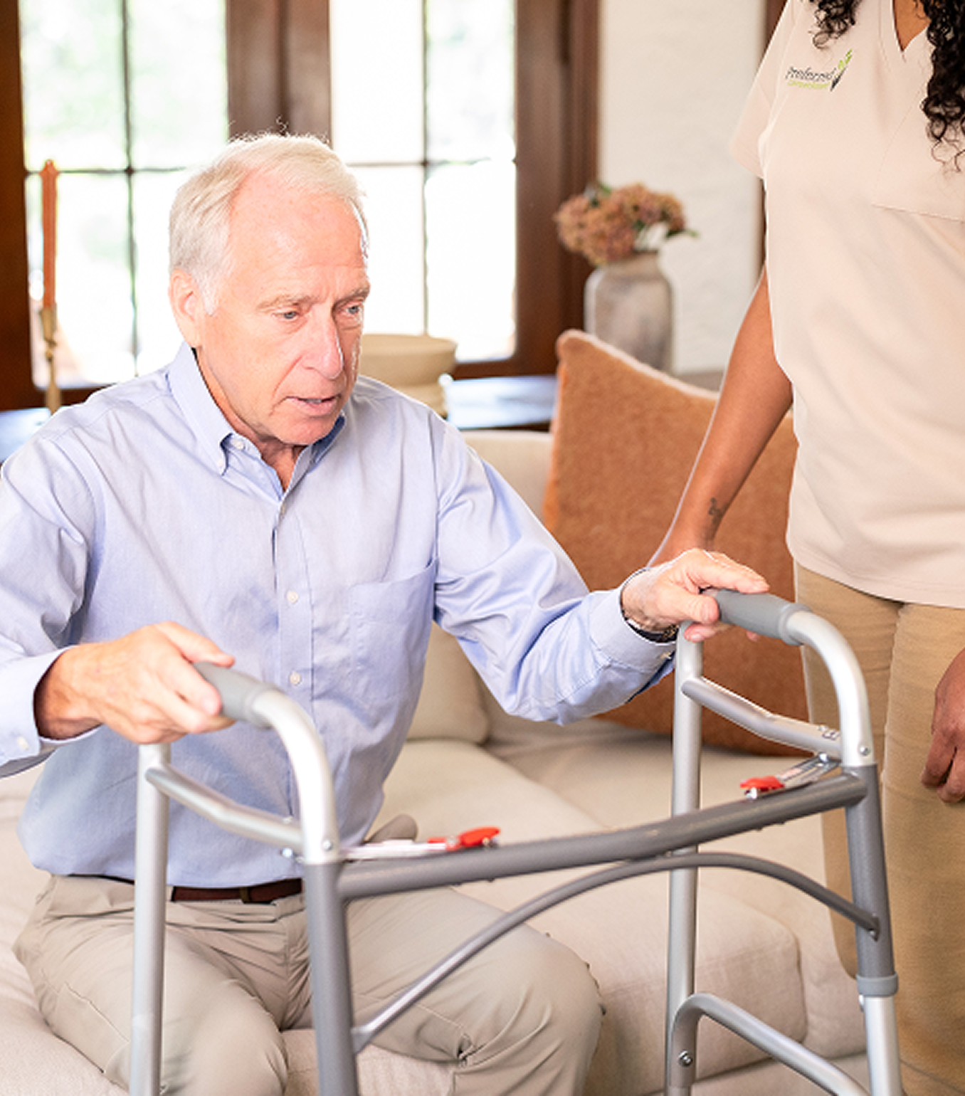 A woman assists an older man using a walker, providing support and guidance as they navigate together.