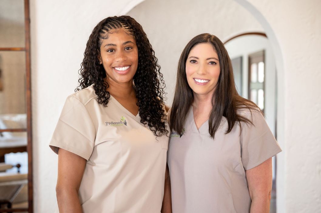Two women in scrubs stand side by side, smiling, representing their careers in healthcare.