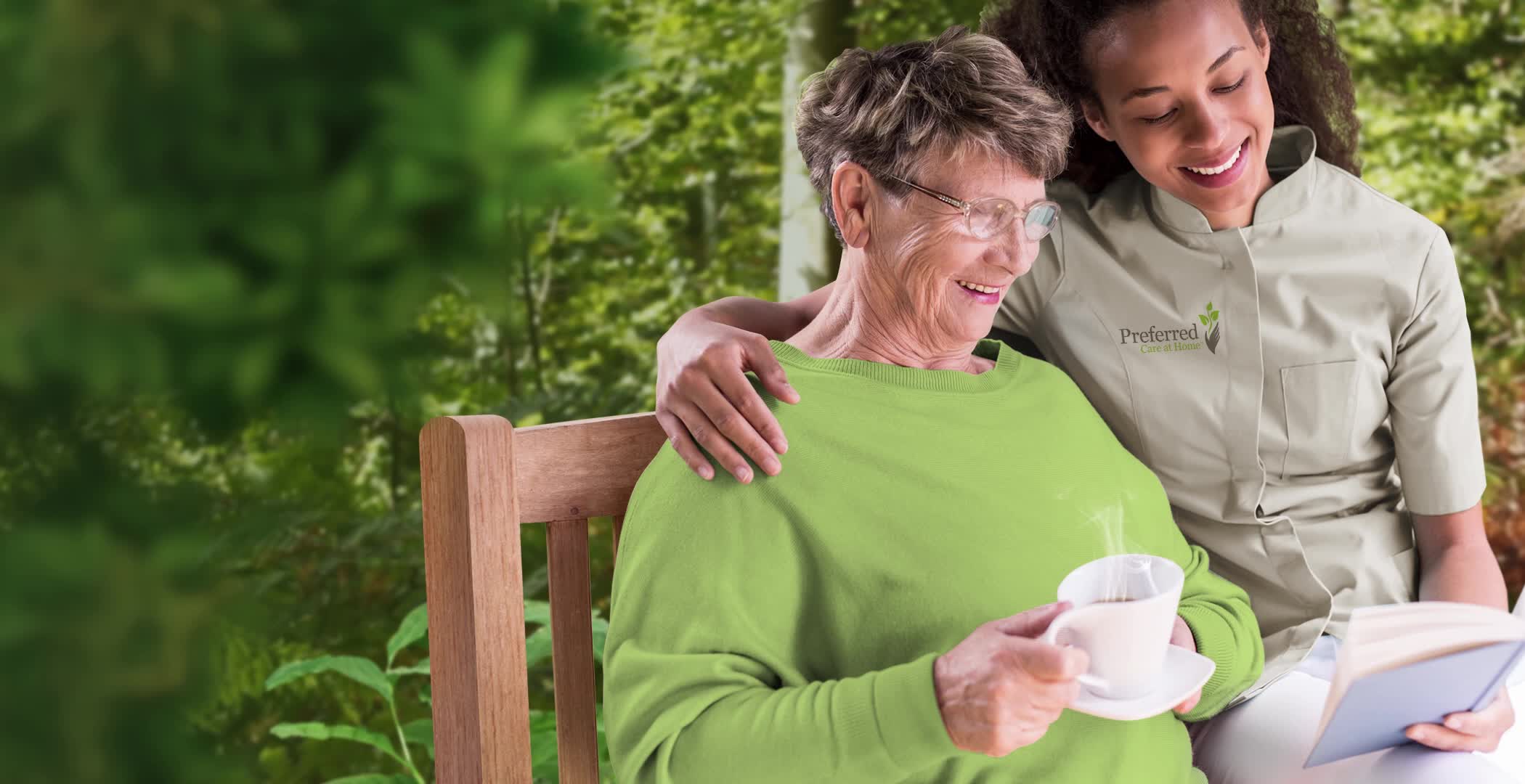 An image of a caregiver from Preferred Care at Home assisting an elderly individual with reading while she enjoys a cup of tea. Preferred Care at Home is a top-rated in-home care provider in Wilton, Connecticut, serving Easton, Darien, New Canaan, Fairfield, Ridgefield, Weston, Redding, and nearby areas.